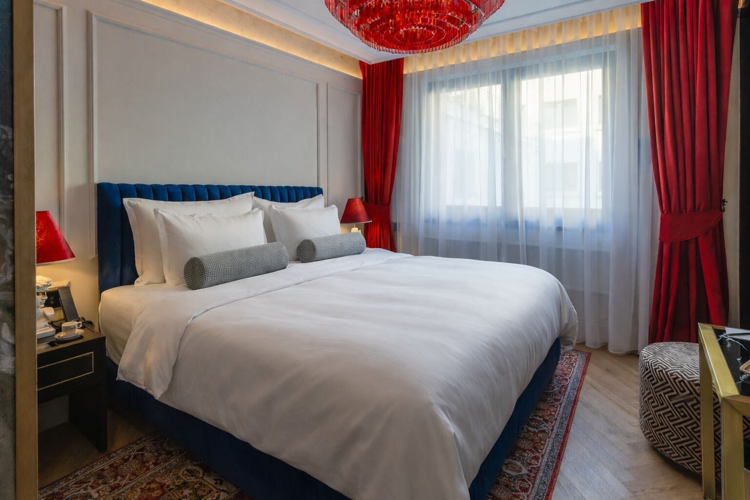 Una habitación de hotel con una cama grande, cortinas rojas y un candelabro rojo.