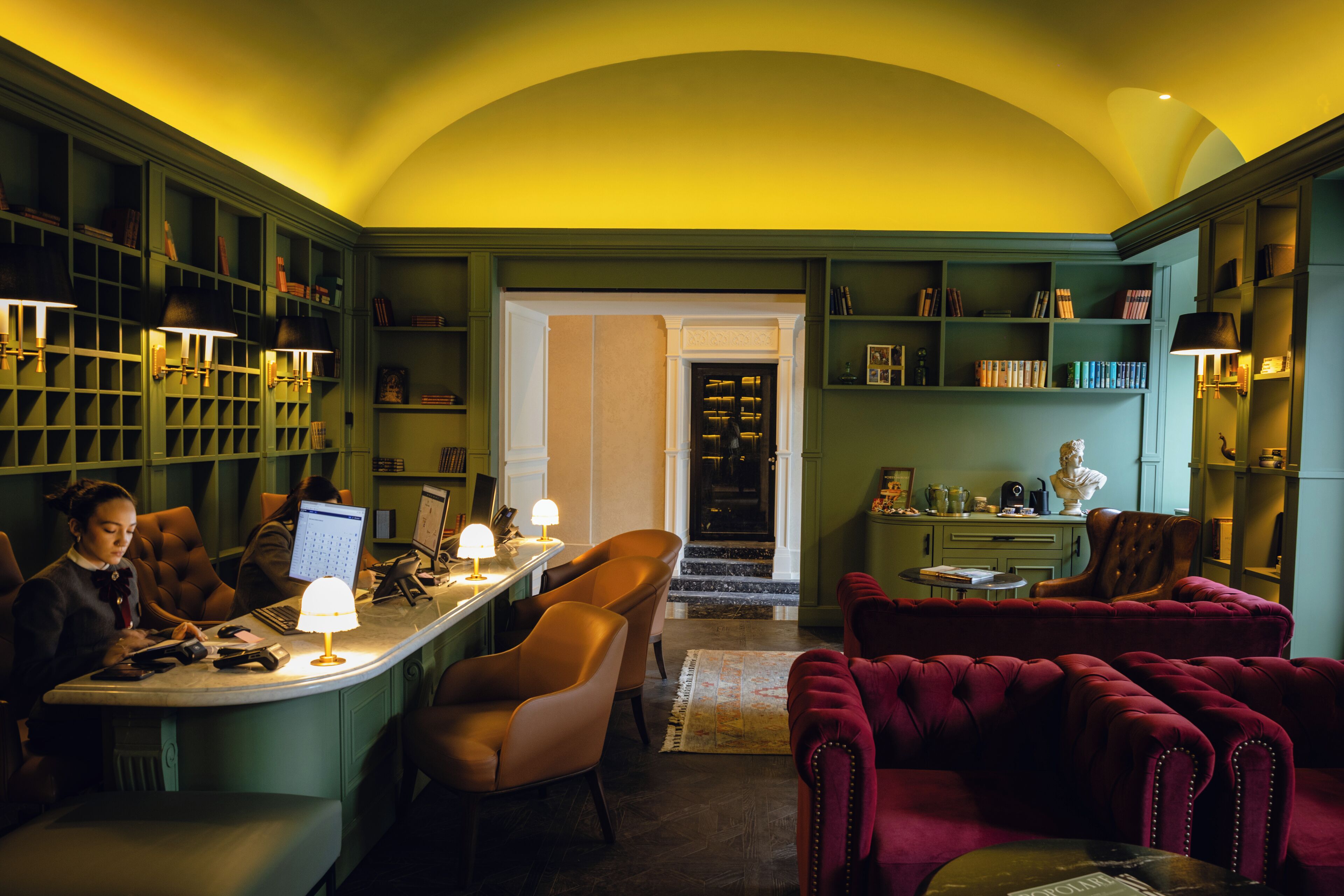 Eine Bibliothek mit Bücherregalen, einer Leseecke mit Sesseln und einem roten Sofa.