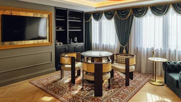 Una sala de estar con una mesa redonda para café, cuatro sillas, un televisor, una estantería y un sofá.