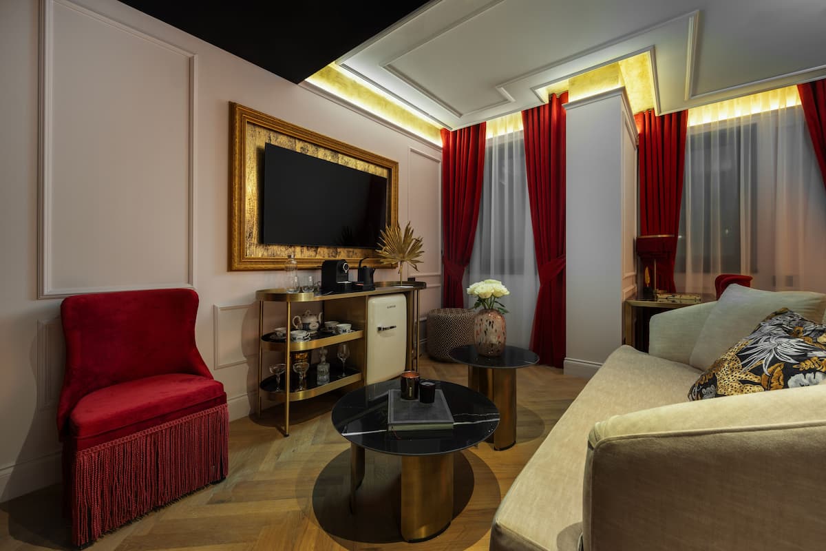 A modern living room with a red armchair, a beige sofa, a black coffee table, and a gold-framed TV.