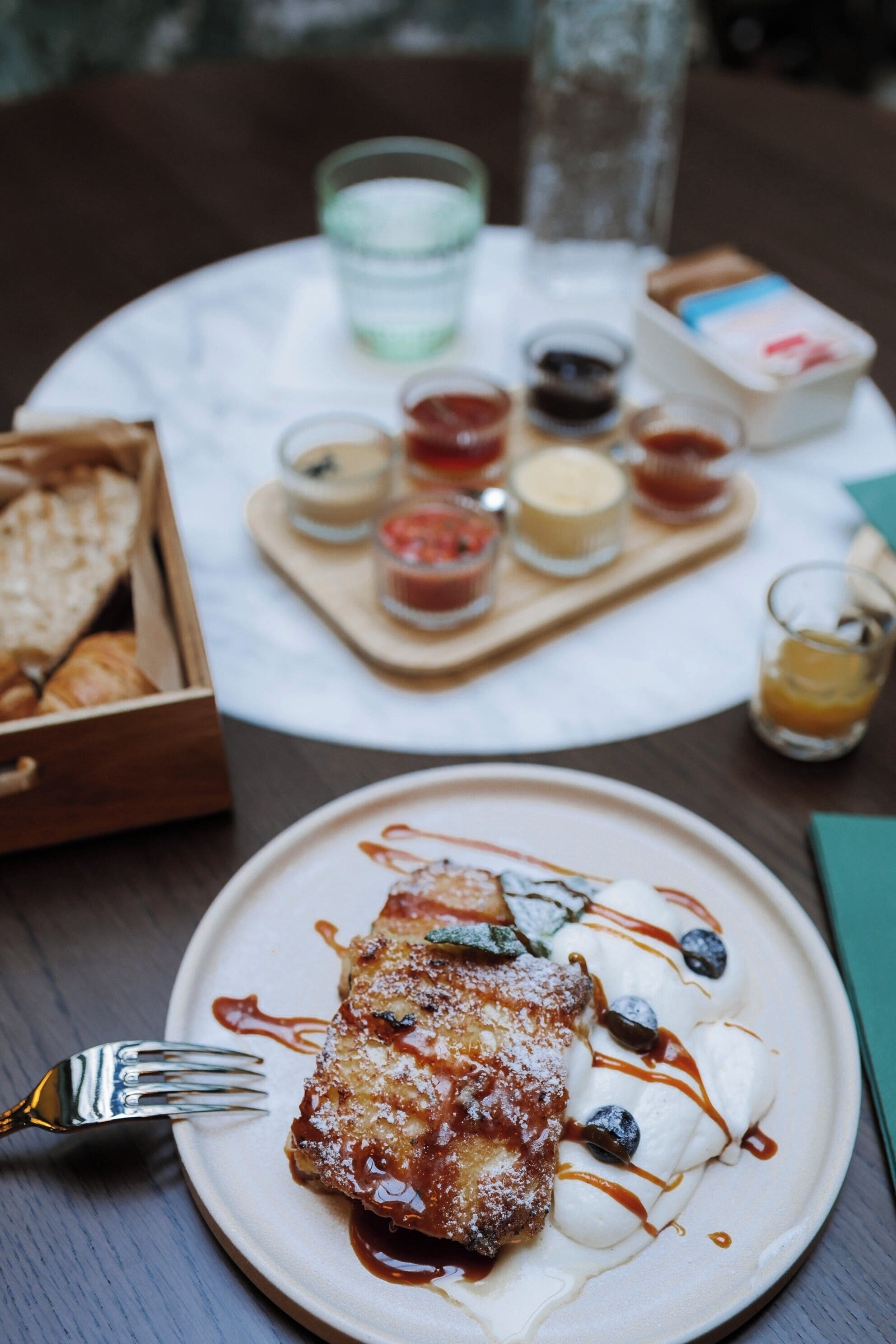 Une table à manger avec une assiette de nourriture, une fourchette et un plateau contenant des condiments.