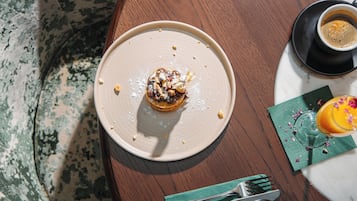 Uma mesa de jantar com um prato de comida, uma xícara de café e um copo de suco de laranja.