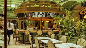 Un ristorante con un bancone centrale, posti a sedere disposti intorno e un pavimento decorato.