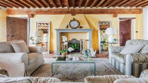 A cozy living room with a fireplace, wooden beams, and comfortable seating. - Villa Giannello – Tuscan Hillside Hideaway (Matraia)
