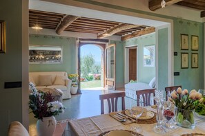 A dining area with a table set for two, a sofa, and a view of the garden.