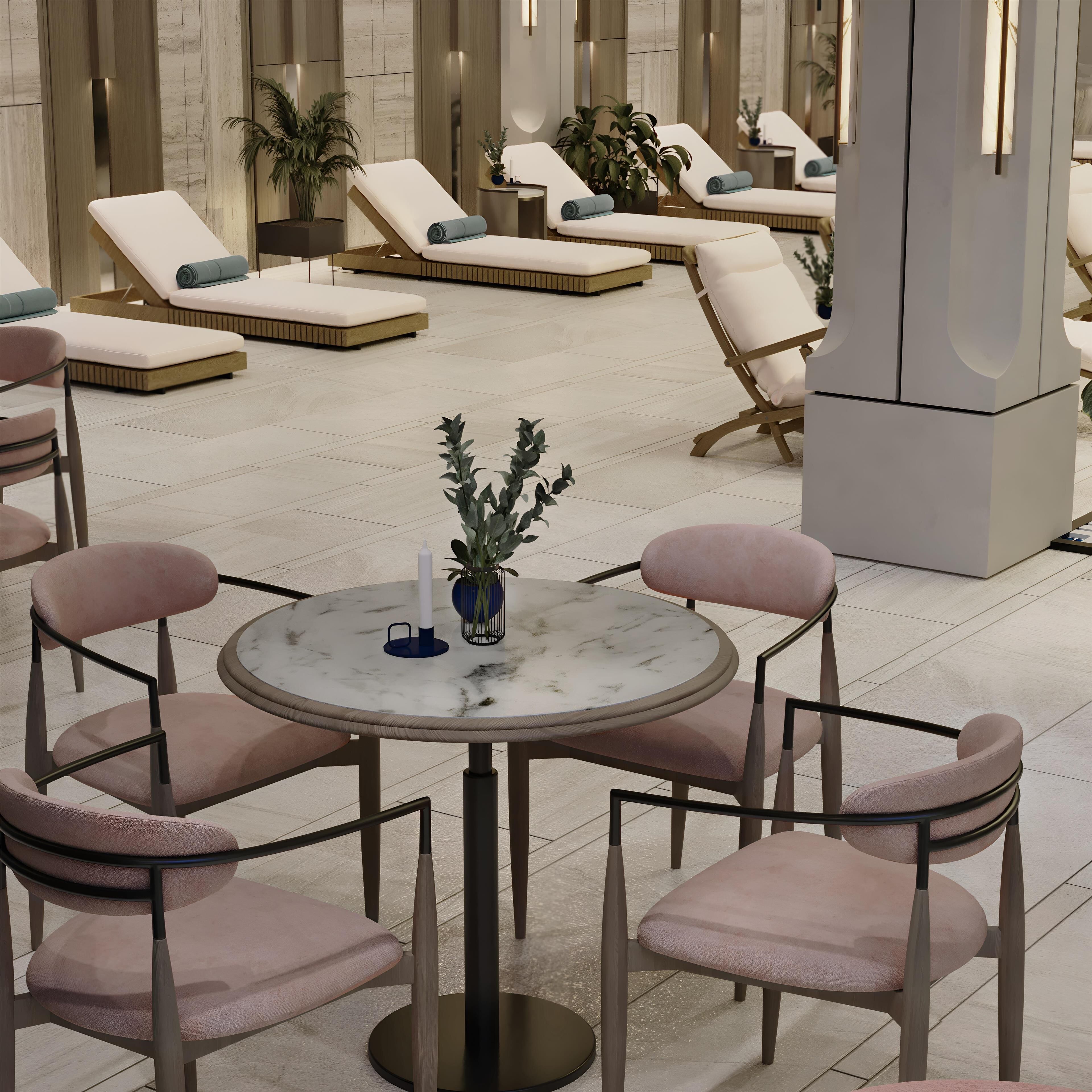 Un área de estar moderna con varias opciones de asientos, incluyendo sillones y una mesa redonda con sillas.