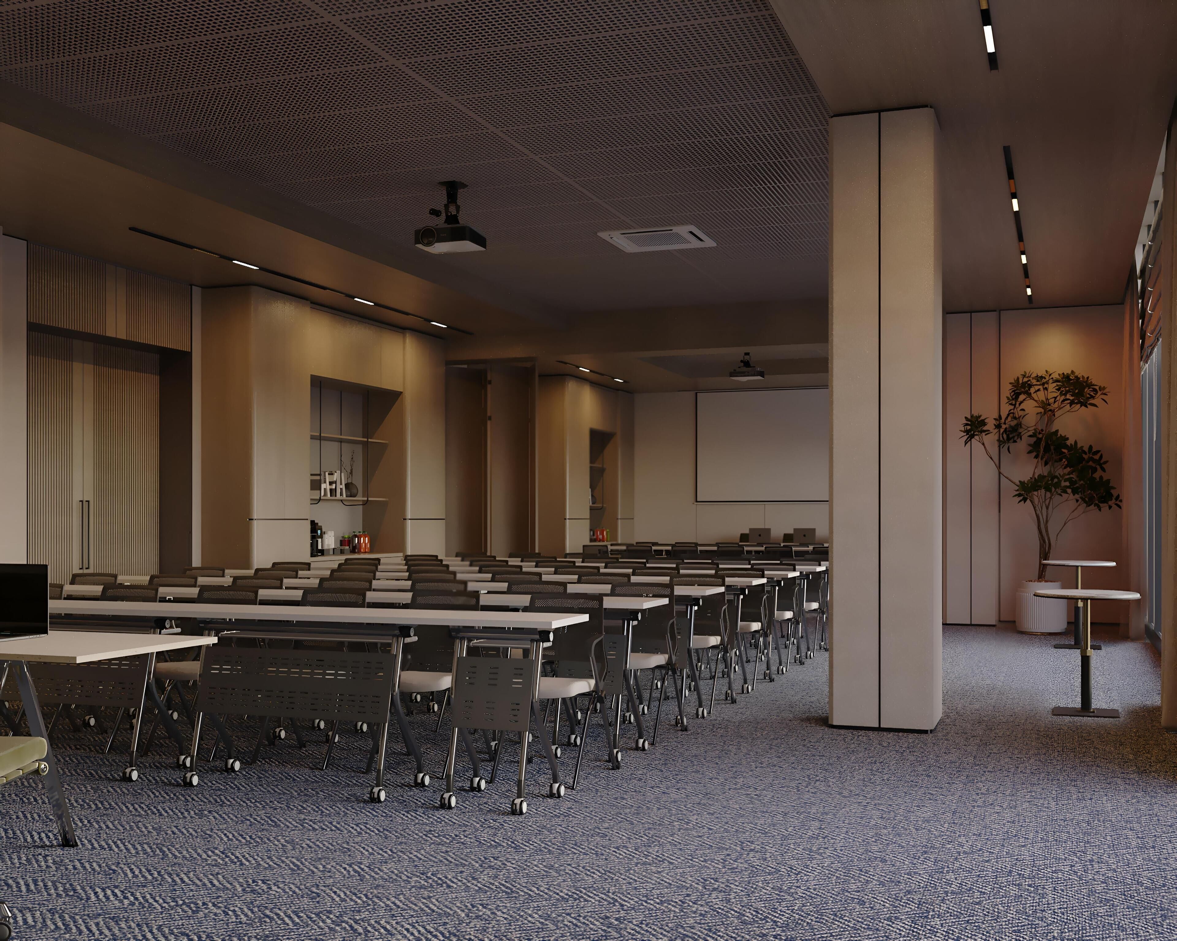A conference room with rows of tables and chairs, a large screen, and a ceiling with a grid pattern.