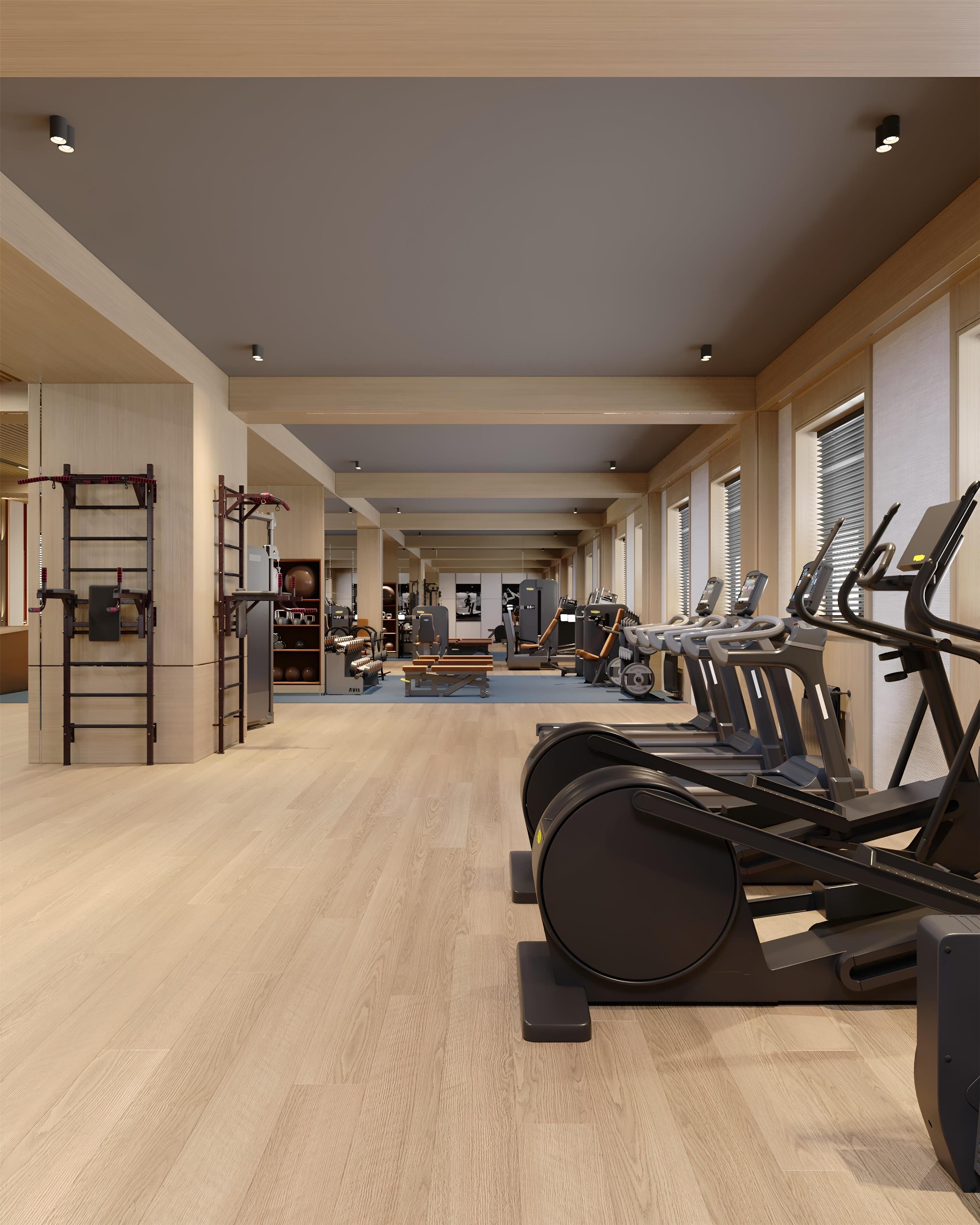 A spacious gym with treadmills, weight machines, and a pull-up bar area.