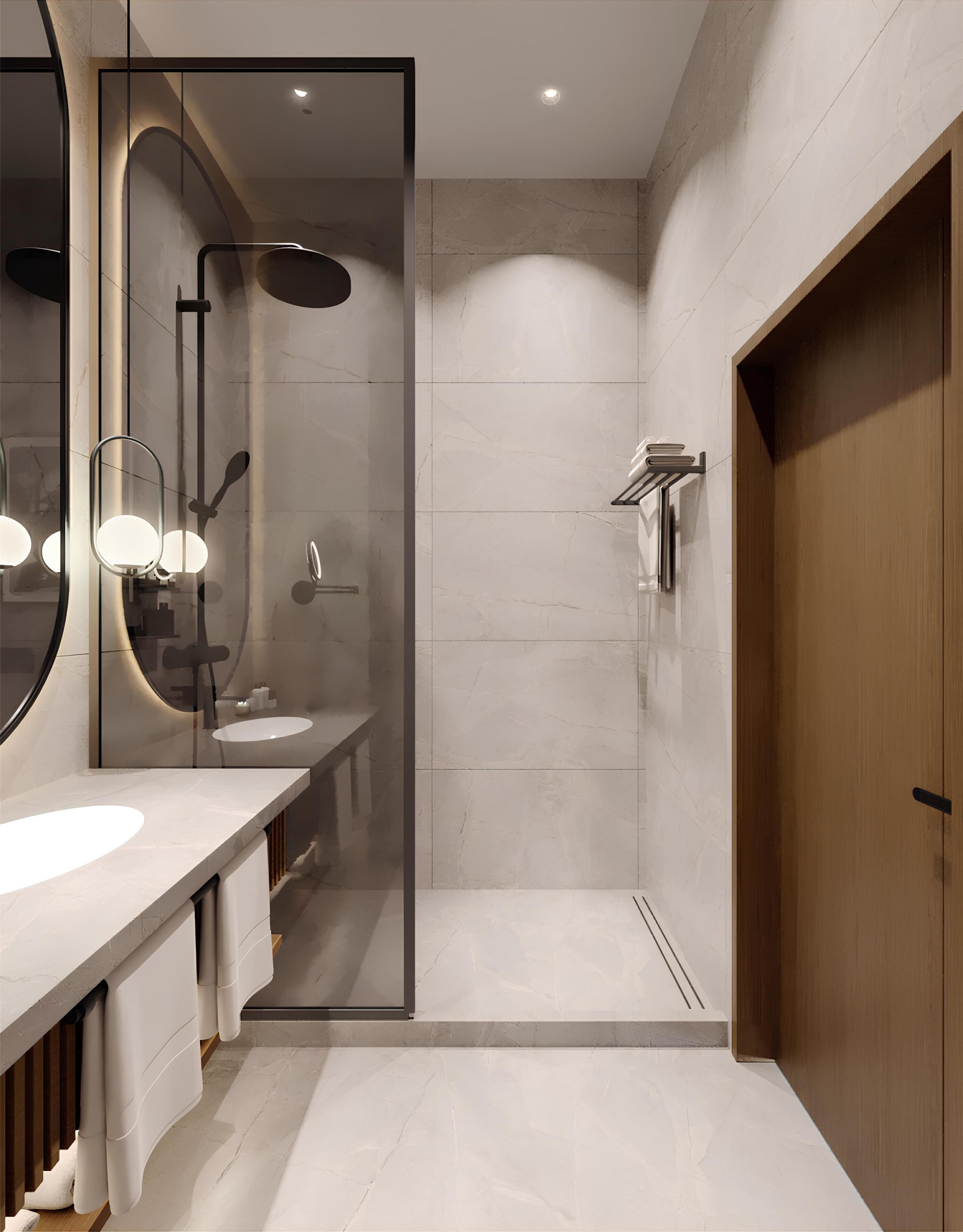 Un baño moderno con ducha envuelta en vidrio, un espejo grande y una puerta de madera.
