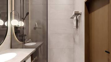 Un baño moderno con ducha envuelta en vidrio, un espejo grande y una puerta de madera.