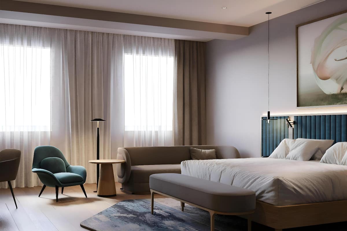 Et moderne soveværelse med en stor seng, en sofa, en stol og et lille bord.
