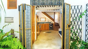 Un pasillo estrecho que da a una cocina con lavadora, armarios de madera y una escalera.