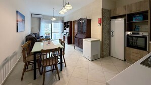 A modern kitchen with a dining area, a refrigerator, an oven, and a built-in cabinet. - Traditional Maltese 3BD Apartment (Nadur)