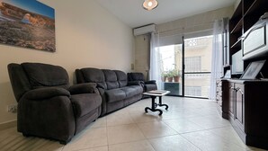 A living room with a sectional sofa, a small table, and a cabinet. - Traditional Maltese 3BD Apartment (Nadur)