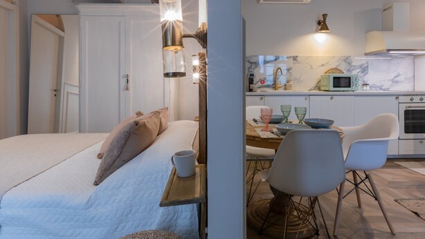 A bedroom with a bed, bedside table, and a nightstand. There is a kitchen area with a microwave, sink, and cabinets. - Design in Corso Francia 2 by Wonderful Italy (Turin)