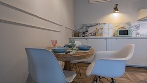 A dining area with a round wooden table, two blue chairs, and a white cabinet in the background. - Design in Corso Francia 2 by Wonderful Italy (Turin)