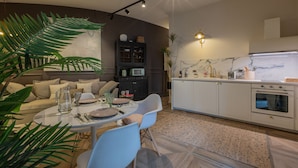 A modern kitchen with white cabinets, a built-in oven, and a marble backsplash.