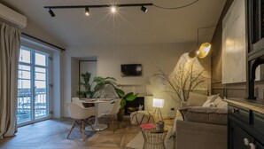A modern living room with a dining area, a fireplace, and a large window with curtains.