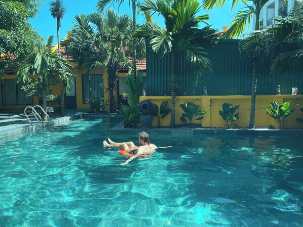 Una piscina al aire libre, sombrillas, sillones reclinables de piscina