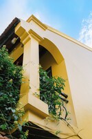 Un edificio amarillo con un balcón y una ventana.