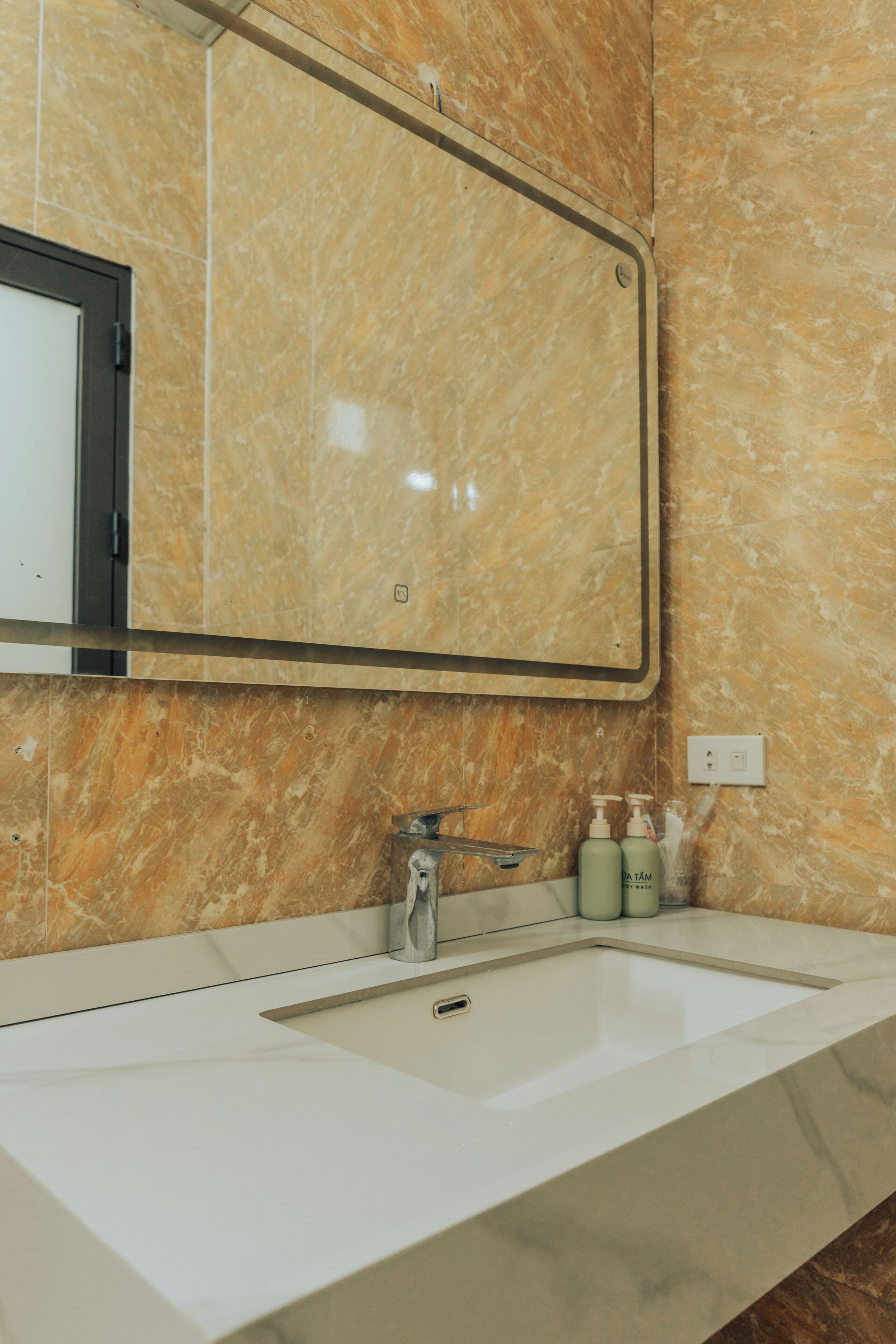 A bathroom with a marble sink, a mirror, and toiletries.