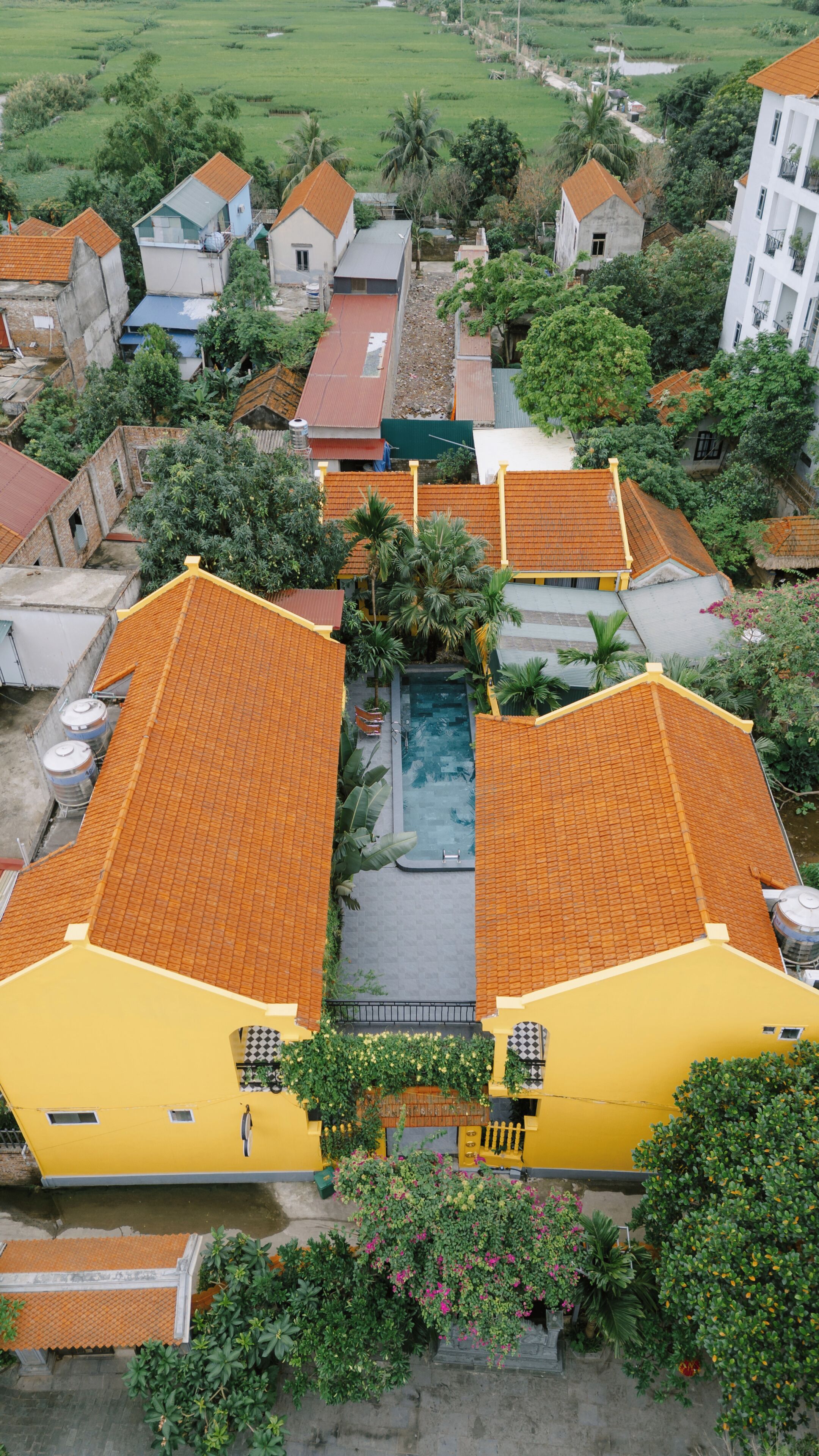 A residential area with houses, a swimming pool, and a large yellow building.