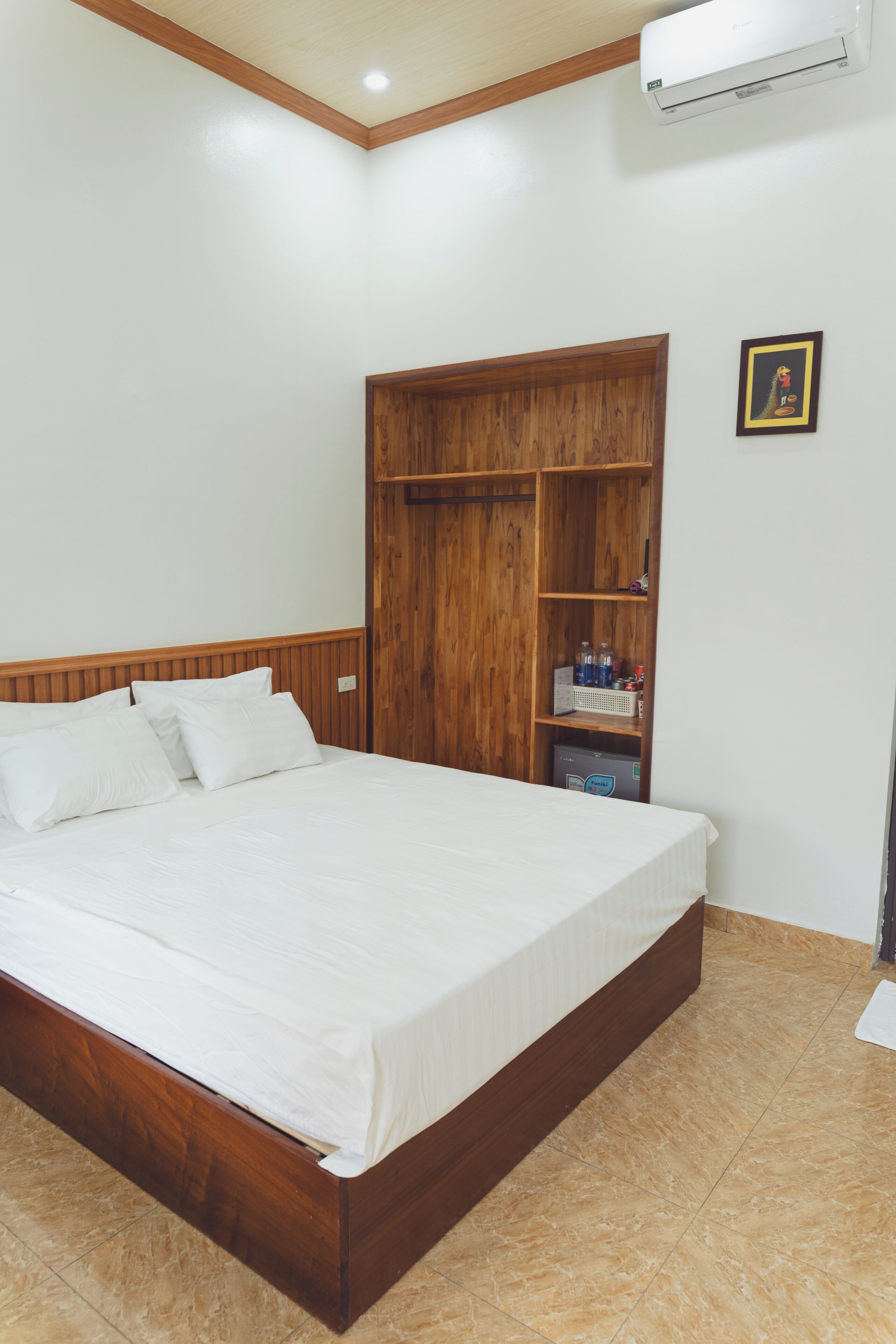 A bedroom with a wooden bed frame, a built-in wardrobe, and a small shelf with bottles.