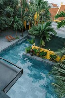 Una piscina rodeada de vegetación y un edificio amarillo.