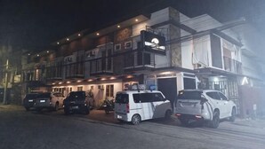 A multi-story building with several parked vehicles in front. - LIVEWIRE PLANET SUITES (General Santos)