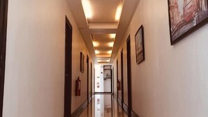A hotel hallway with framed pictures on the walls, a fire extinguisher, and a fire alarm on the wall. - LIVEWIRE PLANET SUITES (General Santos)