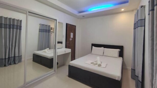 A hotel room with a bed, bedside table, and a mirror. - LIVEWIRE PLANET SUITES (General Santos)