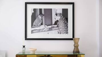 Een zwart-wit foto in een lijst van een cheetah op een glazen tafel met een vaas en een kaars.