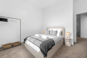 A bedroom with a bed, bedside tables, a wardrobe, and a mirror. - 2 Bed Altrincham Flat | Free Parking (Greater Manchester)