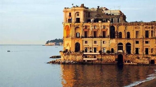 Um edifício histórico com várias arcadas e vista para o rio.