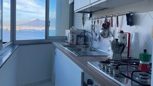 Uma cozinha moderna com uma janela ampla que oferece vista para uma cidade distante e montanhas.