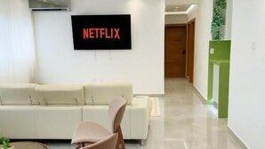 Ein modernes Wohnzimmer mit einem weißen Sofa, einem braunen Sessel und einem flachbildfernseher an der Wand.