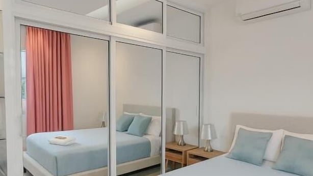 Ein modernes Hotelzimmer mit einem großen Bett, einer separaten Sitzecke mit einer Couch und einer Glastrennwand.