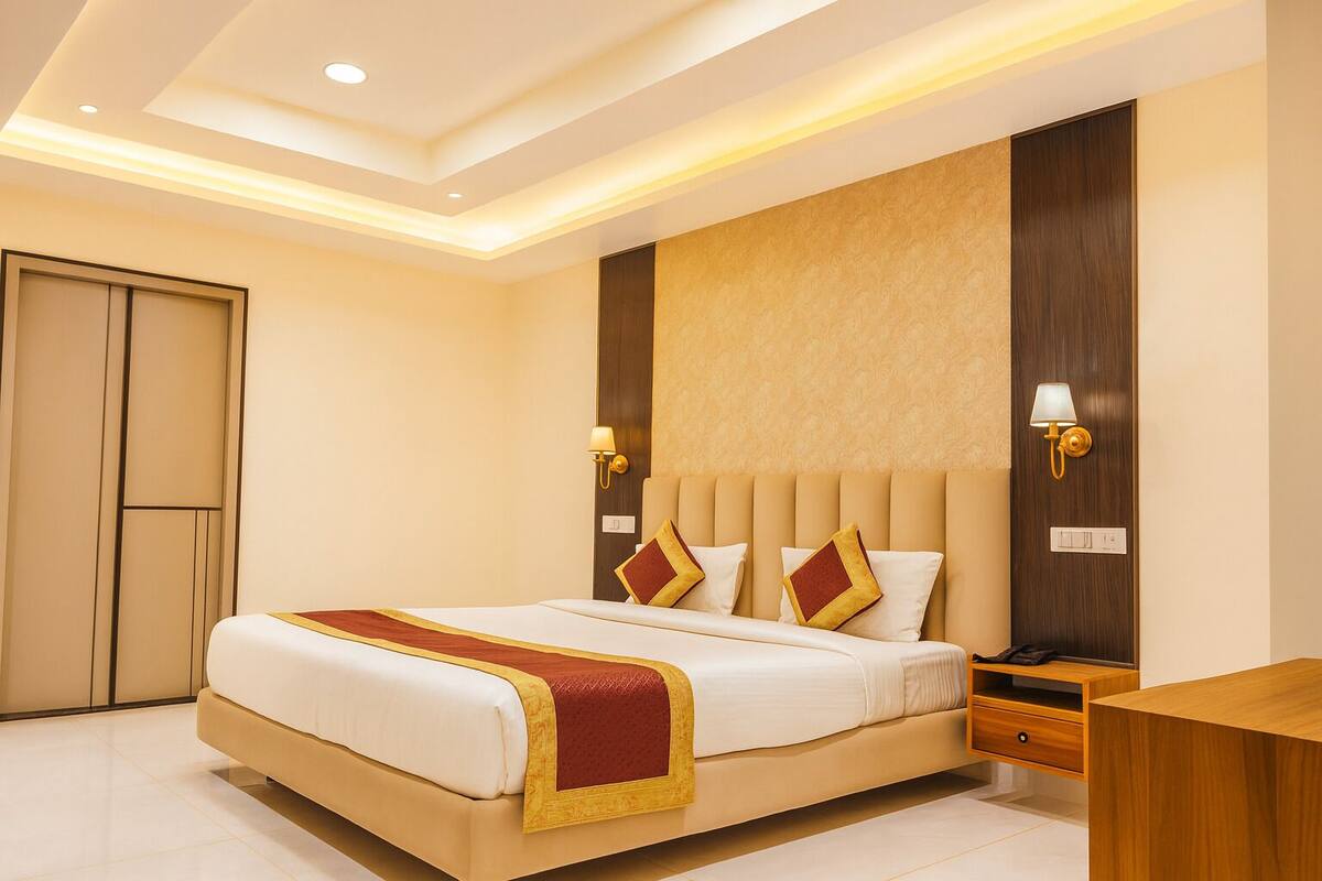 A hotel room with a large bed, a wooden nightstand, a desk, and a wardrobe.