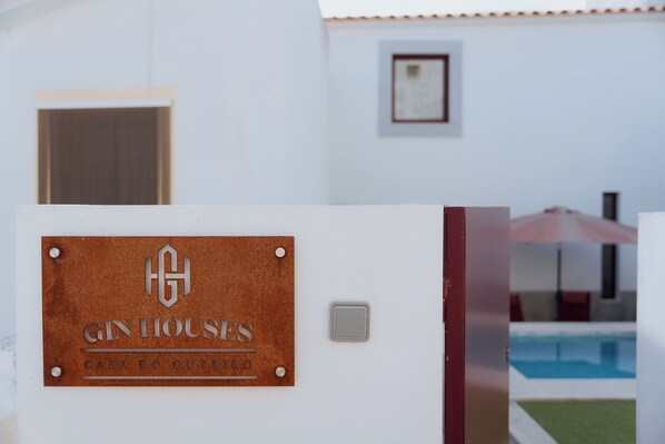 A sign for Gin Houses with a pool in the background. - GinHouses (Marvao)