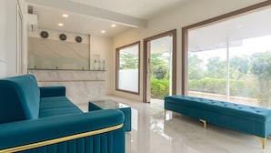 A modern living room with a teal sofa, a matching ottoman, and a marble backsplash. - River Splash Resort Neral Karjat (Karjat)