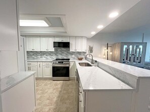 A modern kitchen with white cabinetry, a stainless steel stove, and a tiled backsplash.