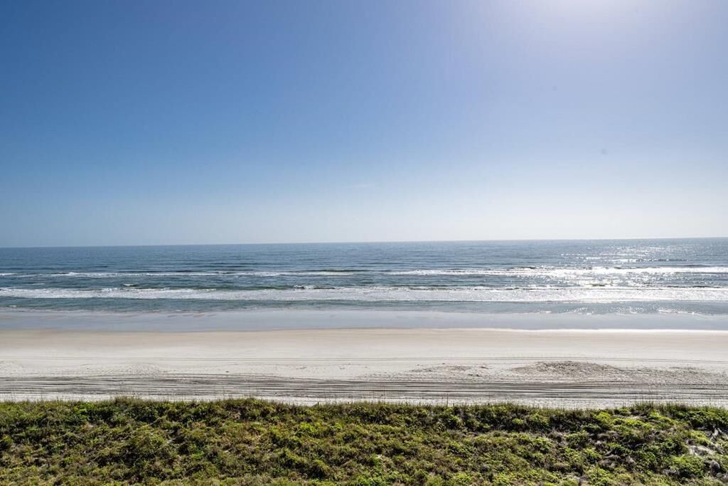Une plage avec un ciel dégagé et des vagues calmes.