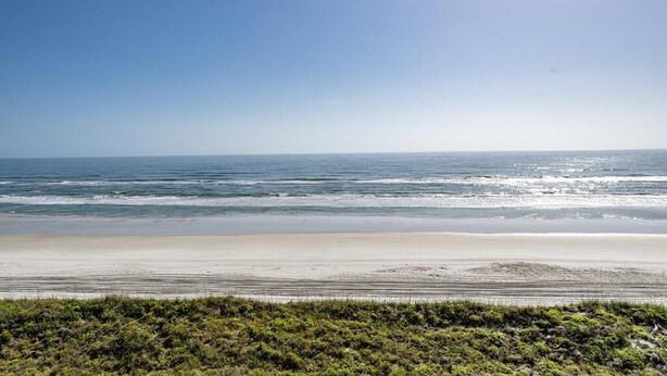 Ein Strand mit blauem Himmel und ruhiger Brandung.