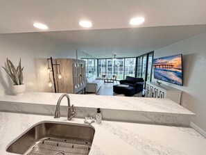 Een moderne keuken met een groot keukeneiland, een inbouwspoelbak en een eetgedeelte met uitzicht op het omliggende landschap.