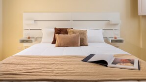 A neatly made bed with a beige bedspread, two pillows, and a book on the bed. - Lùmia Lecce - Urban Residence (Lecce)