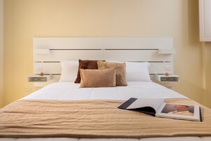 Una cama bien hecha con una colcha color beige, dos almohadas y un libro sobre la cama.