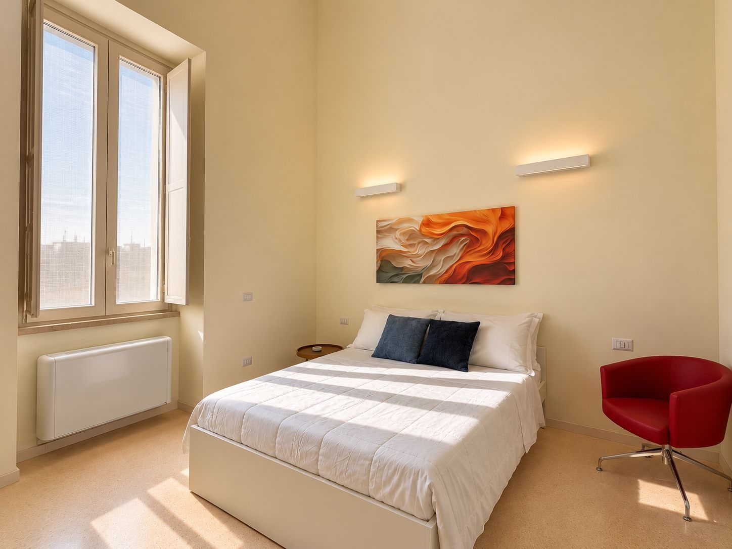 A bedroom with a bed, a red chair, a radiator, and a window with blinds.