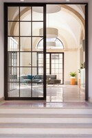 Un interior espacioso con un gran techo abovedado, una zona de estar con sofá y sillones, y una planta en maceta.