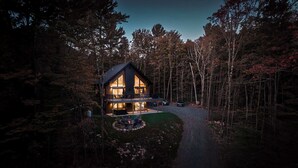 Eine große, zweistöckige Blockhütte mit einer Terrasse und einem Feuerkorb davor.