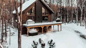Eine Hütte mit einer Veranda, umgeben von Bäumen und bedeckt mit Schnee.
